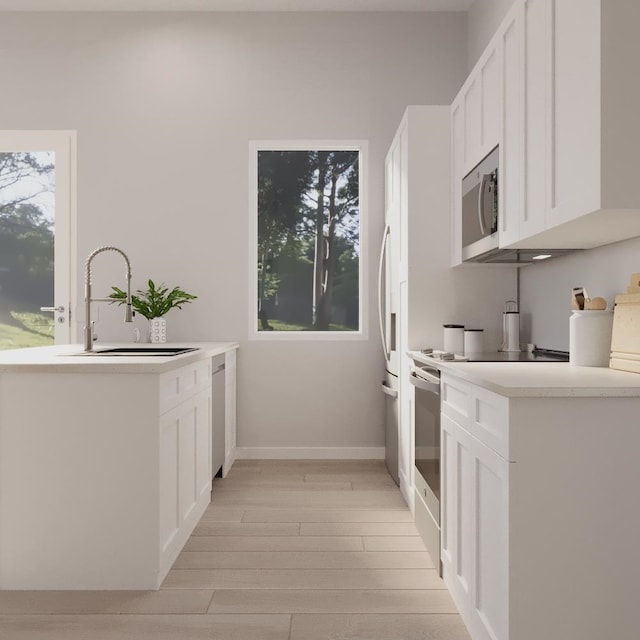 kitchen with electric stove, a wealth of natural light, white cabinets, and light hardwood / wood-style floors