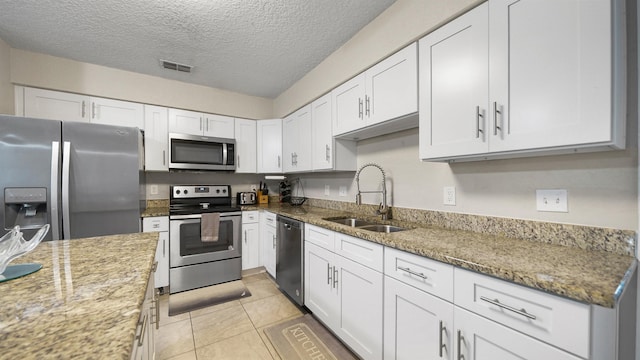 11428 Rustic Pines Cir, Jacksonville, FL 32257 - kitchen featuring appliances with stainless steel finishes, a sink, white cabinets, light stone countertops, and a textured ceiling
