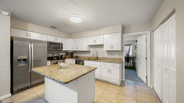 11428 Rustic Pines Cir, Jacksonville, FL 32257 - kitchen featuring stainless steel appliances, a sink, white cabinetry, a center island, and a textured ceiling