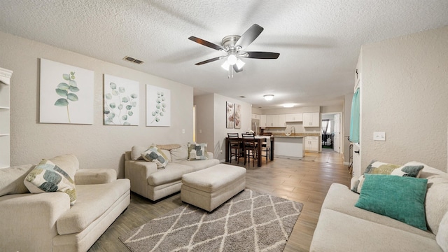 11428 Rustic Pines Cir, Jacksonville, FL 32257 - living area with a ceiling fan, a textured wall, a textured ceiling, and light wood-style floors