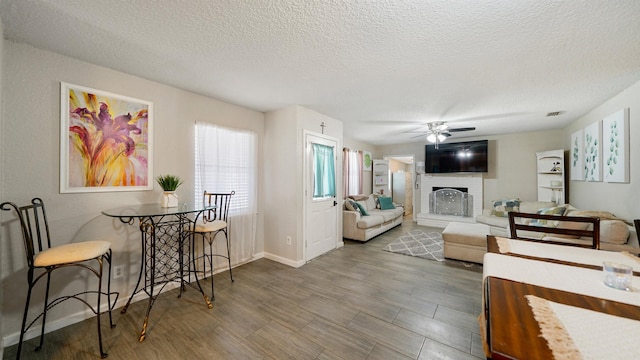 11428 Rustic Pines Cir, Jacksonville, FL 32257 - living area featuring ceiling fan, a brick fireplace, a textured ceiling, baseboards, and wood finished floors