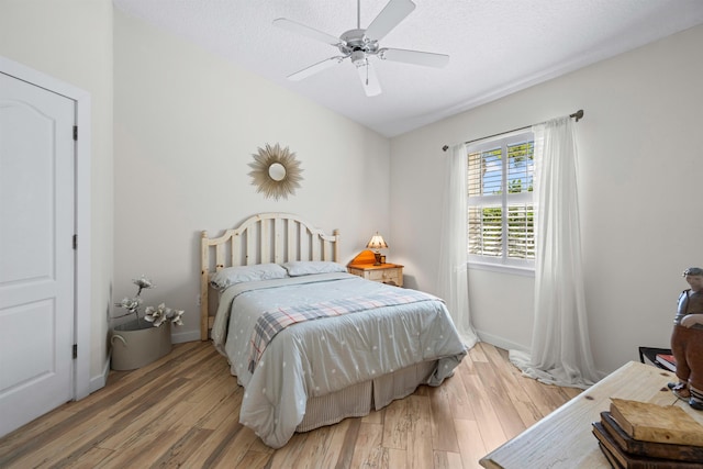 bedroom featuring baseboards, a textured ceiling, wood finished floors, and a ceiling fan