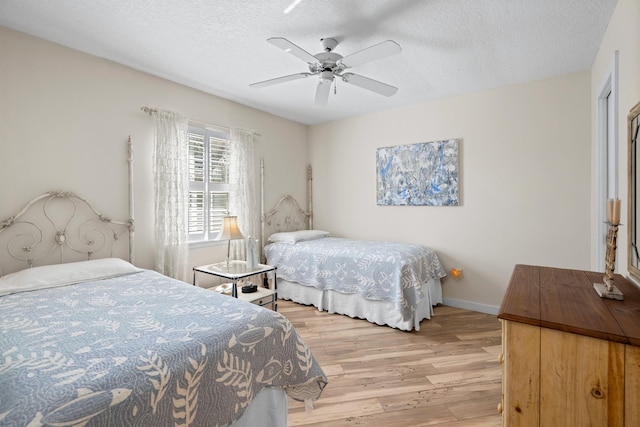 bedroom with light wood-style flooring, a textured ceiling, baseboards, and ceiling fan