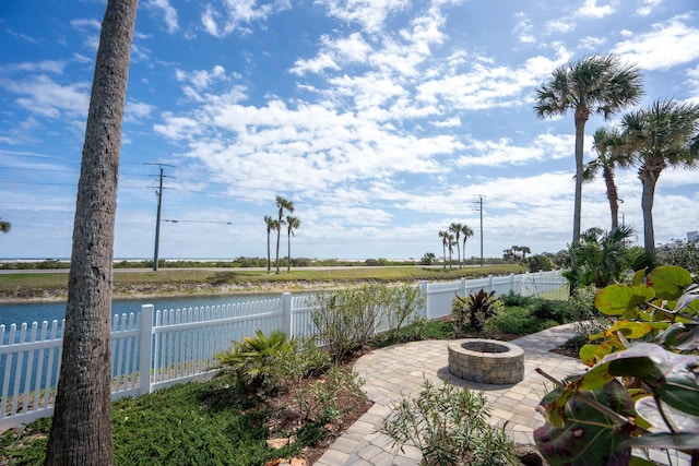 view of patio / terrace with a water view, a fenced backyard, and an outdoor fire pit