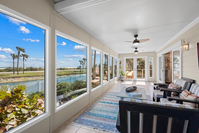 sunroom featuring a ceiling fan and a water view