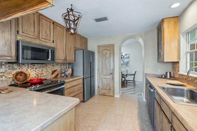 kitchen with visible vents, light countertops, appliances with stainless steel finishes, arched walkways, and a sink