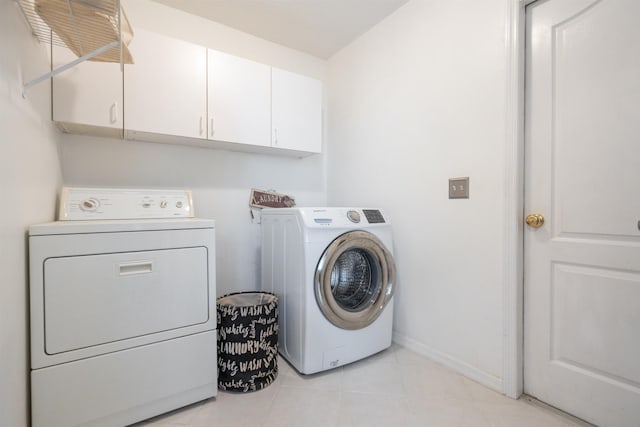 clothes washing area featuring light tile patterned floors, baseboards, cabinet space, and independent washer and dryer