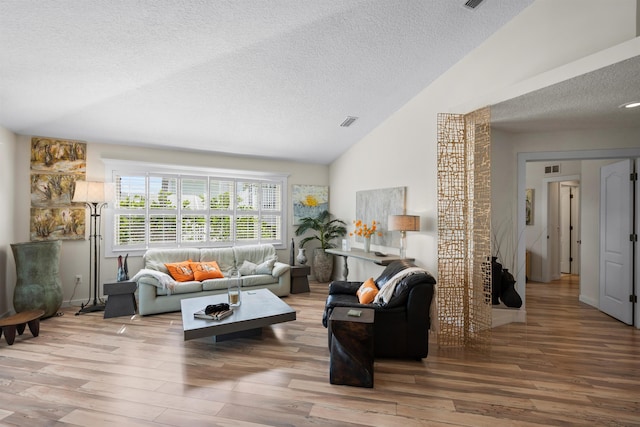 living room featuring vaulted ceiling, wood finished floors, visible vents, and a textured ceiling