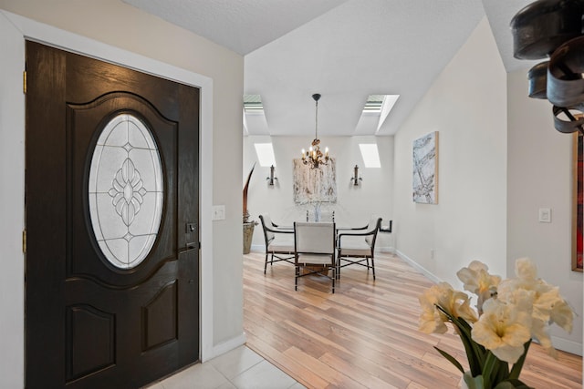 entryway featuring a notable chandelier, baseboards, and light wood-type flooring