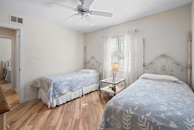 bedroom featuring visible vents, a textured ceiling, wood finished floors, and a ceiling fan