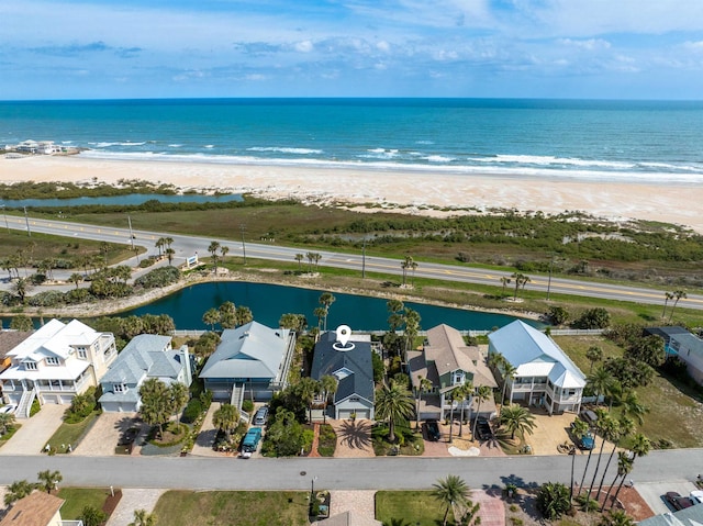 drone / aerial view featuring a view of the beach, a water view, and a residential view