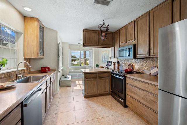 kitchen featuring visible vents, a sink, appliances with stainless steel finishes, a peninsula, and light tile patterned floors