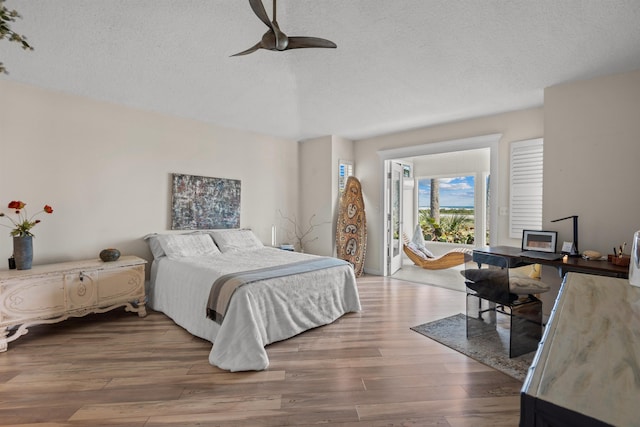 bedroom with a textured ceiling, ceiling fan, and wood finished floors