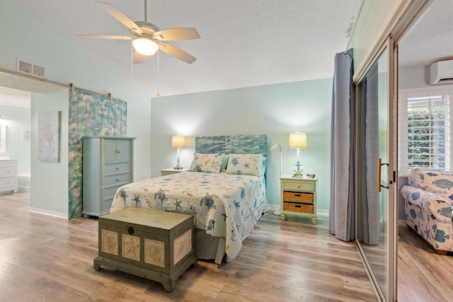 362 Monika Pl, Saint Augustine, FL 32080 - bedroom with a wall mounted AC, wood-type flooring, a textured ceiling, vaulted ceiling, and a barn door