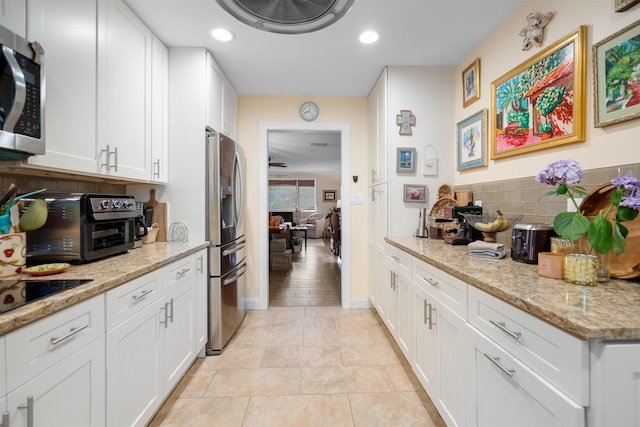 kitchen with white cabinetry, light tile patterned floors, stainless steel appliances, and light stone counters