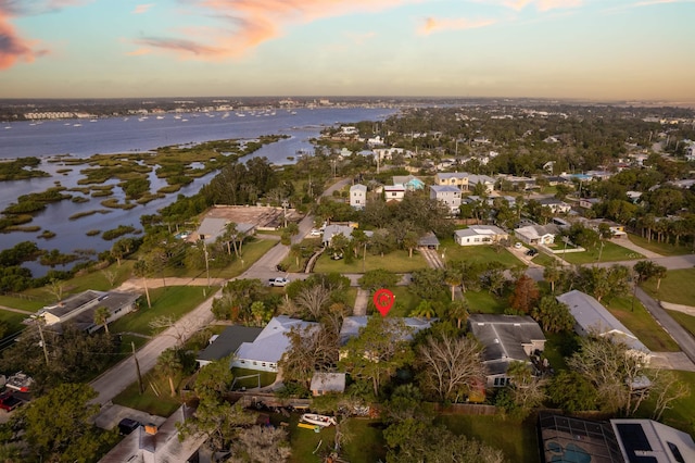 aerial view at dusk featuring a water view