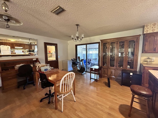 dining area with a notable chandelier, light hardwood / wood-style floors, and a textured ceiling