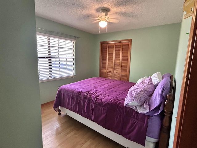 bedroom with ceiling fan, a closet, wood-type flooring, and a textured ceiling