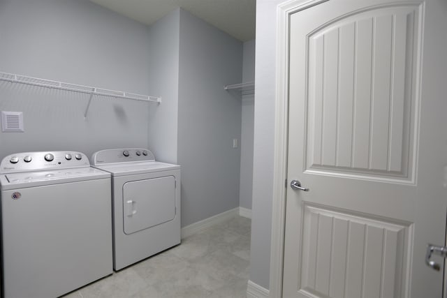 clothes washing area with separate washer and dryer and light tile patterned floors