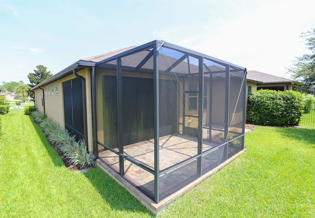 exterior space featuring a patio, glass enclosure, and a lawn