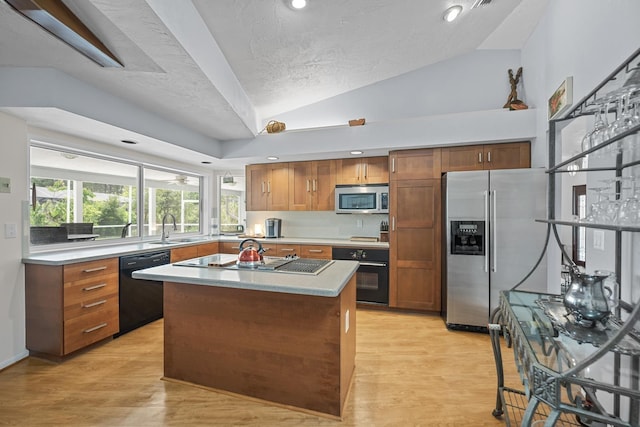 kitchen with a sink, black appliances, light countertops, and a center island