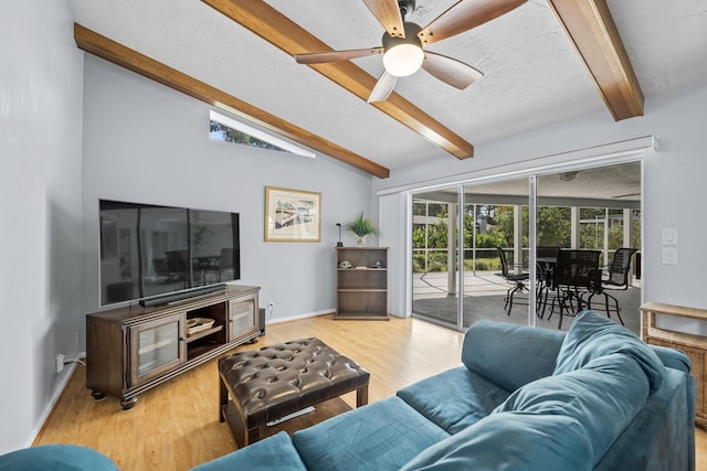 living room with a ceiling fan, vaulted ceiling with beams, baseboards, and wood finished floors