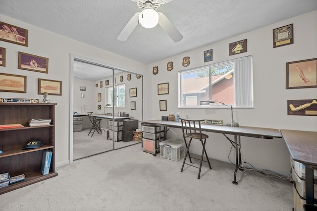 office space with ceiling fan, a textured ceiling, a wealth of natural light, and light colored carpet