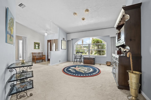 living area with baseboards, visible vents, vaulted ceiling, and light colored carpet