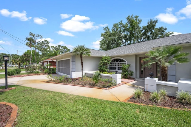 ranch-style home with an attached garage, concrete driveway, roof with shingles, stucco siding, and a front yard