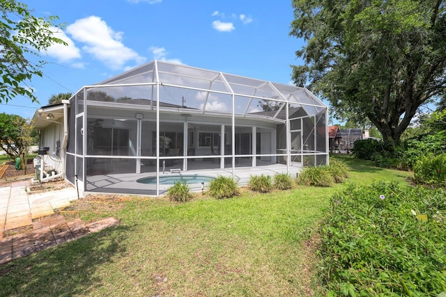 back of property with glass enclosure, a lawn, a patio, and an outdoor pool