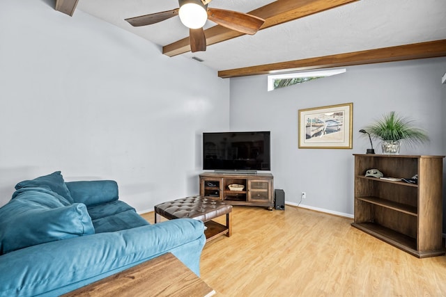 living room featuring ceiling fan, visible vents, baseboards, beam ceiling, and light wood finished floors