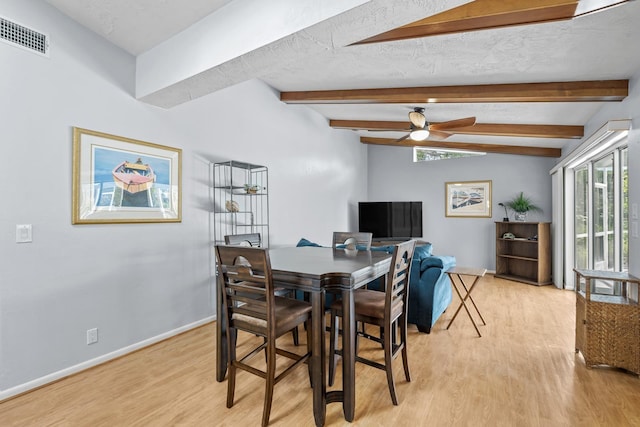 dining space with vaulted ceiling with beams, visible vents, light wood-style flooring, a textured ceiling, and baseboards