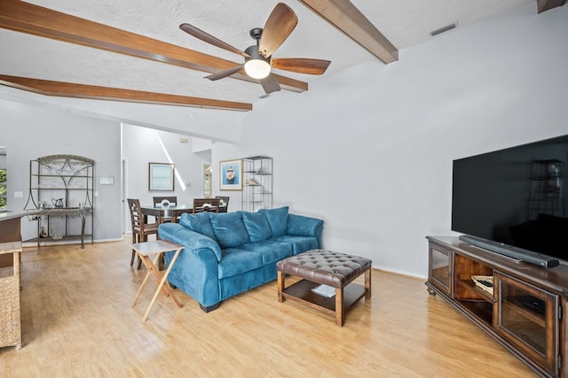 living area featuring vaulted ceiling with beams, a textured ceiling, and light wood finished floors