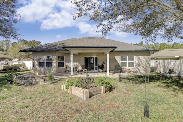 back of property with a vegetable garden, a patio, a lawn, fence, and a fire pit