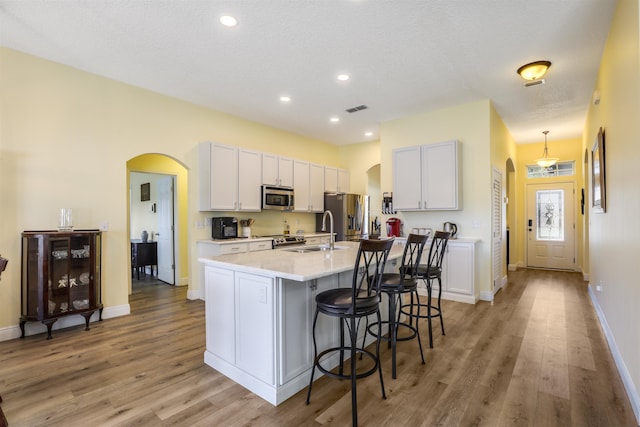 kitchen with visible vents, arched walkways, stainless steel appliances, and a sink