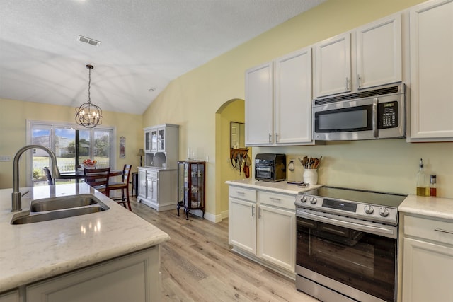 kitchen featuring arched walkways, a sink, visible vents, vaulted ceiling, and appliances with stainless steel finishes