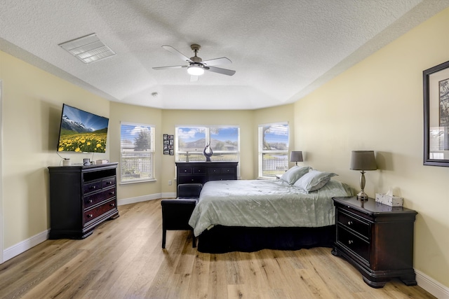 bedroom featuring a textured ceiling, light wood finished floors, and baseboards