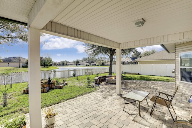 view of patio / terrace featuring a water view, a fenced backyard, and a fire pit