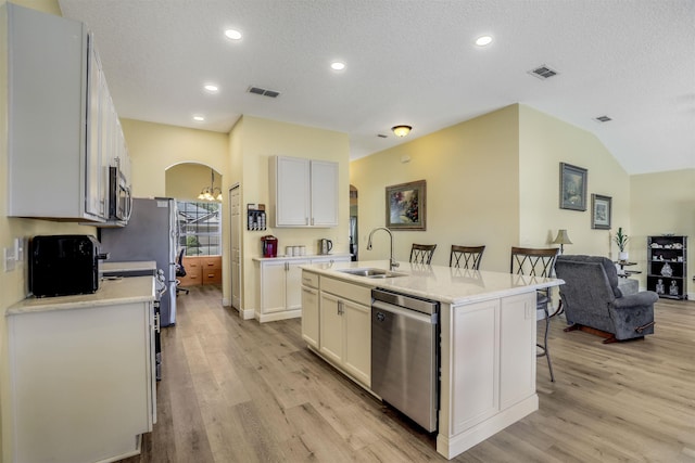 kitchen with arched walkways, a breakfast bar, stainless steel appliances, visible vents, and a sink