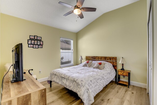 bedroom featuring light wood-type flooring, baseboards, vaulted ceiling, and a ceiling fan