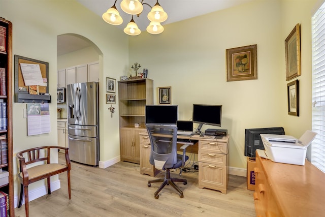 office area featuring an inviting chandelier, light wood-style flooring, arched walkways, and baseboards