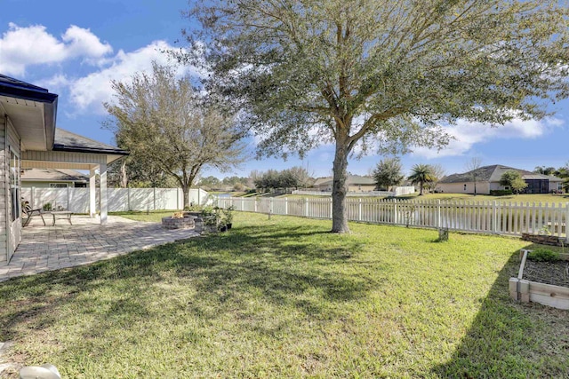 view of yard featuring a patio area, a fenced backyard, and a water view