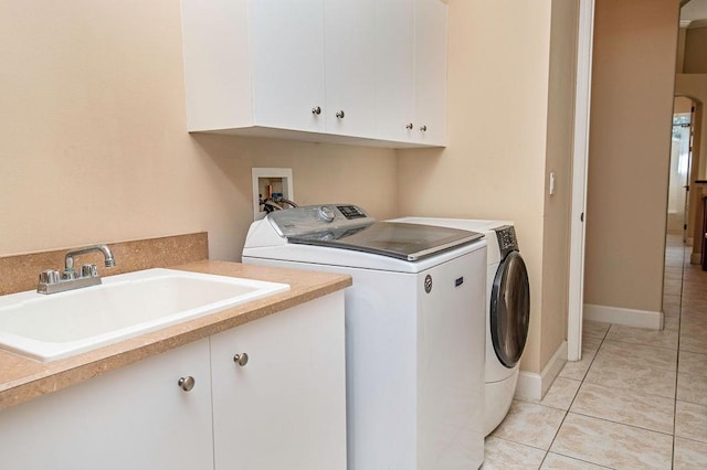 clothes washing area with washer and clothes dryer, light tile patterned floors, cabinets, and sink