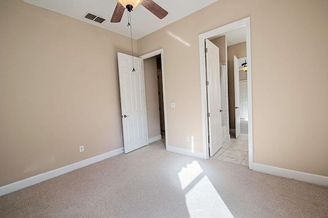 unfurnished bedroom with ceiling fan, light colored carpet, and ensuite bathroom