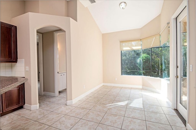 unfurnished dining area featuring light tile patterned floors and vaulted ceiling