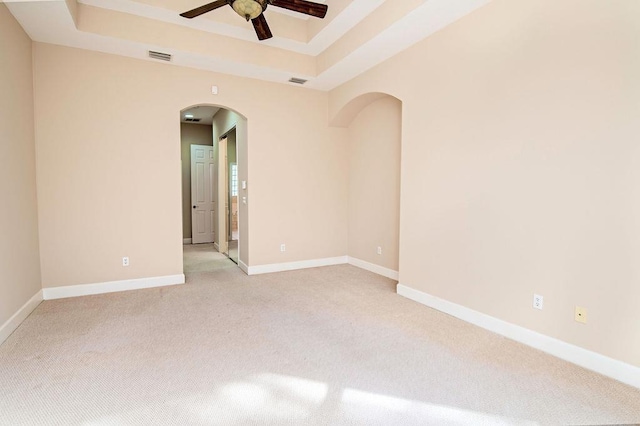 carpeted empty room featuring a tray ceiling and ceiling fan