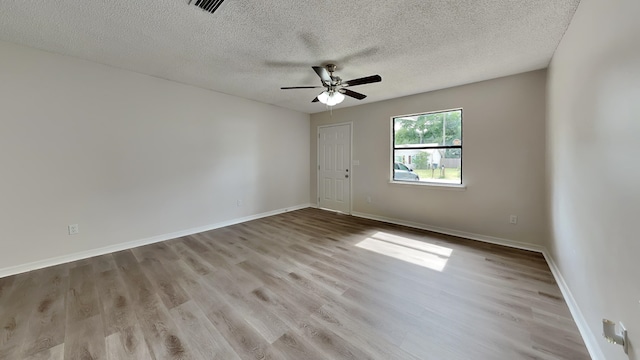 spare room with ceiling fan, a textured ceiling, and light wood-type flooring