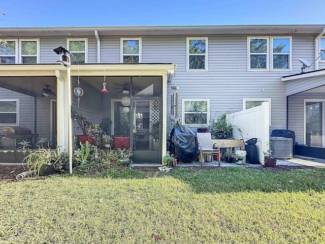 rear view of house with a ceiling fan, a sunroom, and a lawn