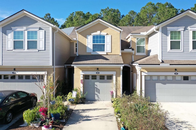 multi unit property with a garage, concrete driveway, a shingled roof, and stucco siding