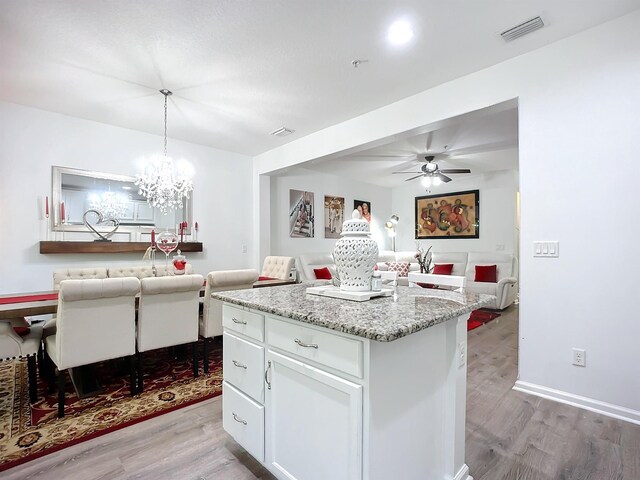 kitchen with a center island, visible vents, light wood-style floors, open floor plan, and white cabinetry